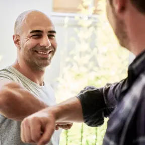 Two men smiling at each other in front of a house offering fast WordPress hosting.